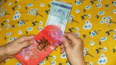 Rm100, Rm50 notlar, Malezya para kırmızı paket para birimiyle holding kadınlar eller. Seçilen odak. Yakın çekim.