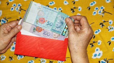 Rm100, Rm50 notlar, Malezya para kırmızı paket para birimiyle holding kadınlar eller. Seçilen odak. Yakın çekim.