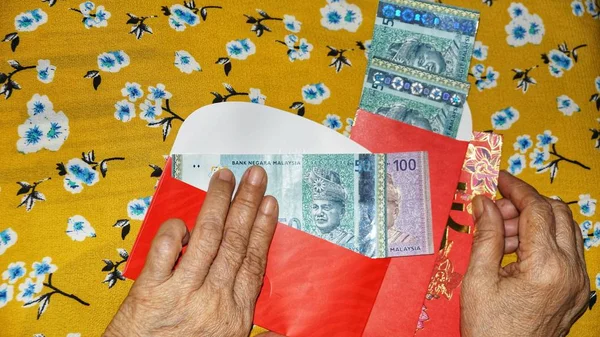 Rm100, Rm50 notlar, Malezya para kırmızı paket para birimiyle holding kadınlar eller. Seçilen odak. Yakın çekim.