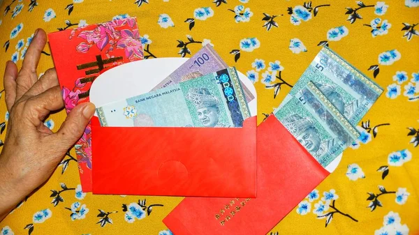 Rm100, Rm50 notlar, Malezya para kırmızı paket para birimiyle holding kadınlar eller. Seçilen odak. Yakın çekim.