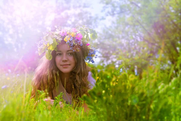 在草地上 她的头上有一个花环花圈的年轻女孩 一个年轻女孩在她的头上的花朵花环 免版税图库照片