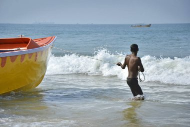 Bir adam koyu tenli bir tekne deniz tutar. Hindu ve tekne deniz