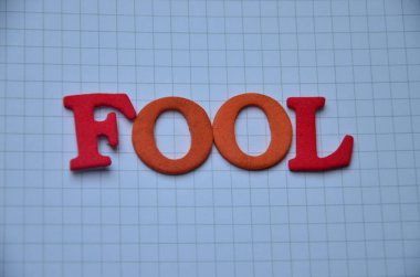 Beyaz arka planda ahşap harflerden yapılmış aptal kelimesi.