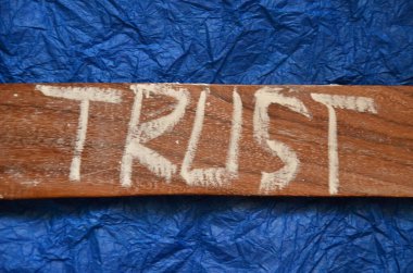 Güven kelimesi soyut ahşap arkaplanda yazılı.