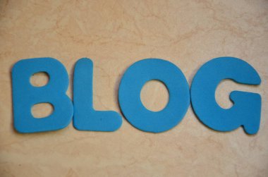 Tahta bloktan yazılmış blog kelimesi. Masanın üzerinde ahşap bir tabela var. desing konseptin.