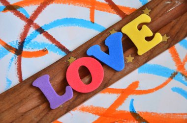 Ahşap arka planda kalpten gelen renkli bir aşk kelimesi