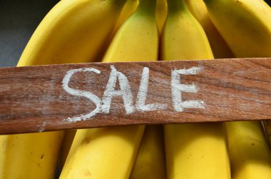 sale word on a black banana on a wooden board