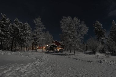 Finlandiya, Inari - Ocak 2019: Donmuş gölün kenarındaki Otel'den Gelen ışıkları karşılayan, mehtaplı kış manzarası