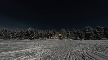 Finlandiya, Inari - Ocak 2019: Donmuş gölün kenarındaki Otel'den Gelen ışıkları karşılayan, mehtaplı kış manzarası