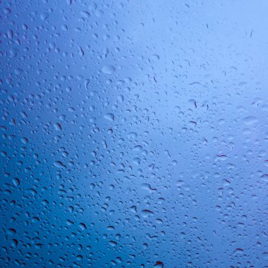 Arka plan olarak cam yüzeyinde mavi su damlaları.