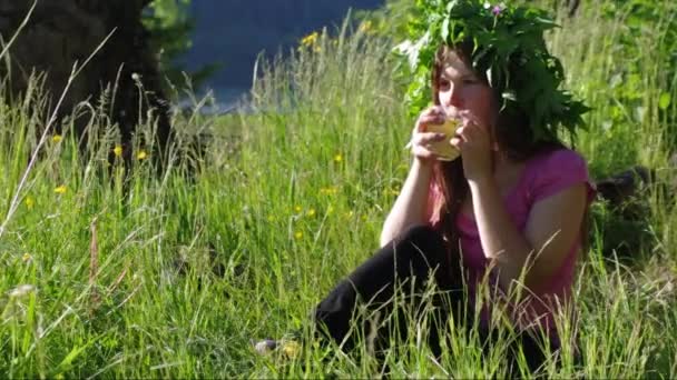 一个年轻的女孩正在草地上喝草药茶 — 图库视频影像