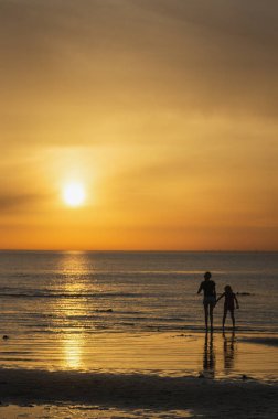 Çocuk denizde günbatımında oyun..