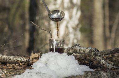 Pouring syrup from birch sap into a glass. clipart