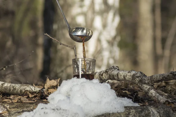 Huş özsuyundan bir bardağa şurup dökme.