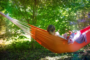 Bir ormanın ortasında hamakta rahatlatıcı, gün batımından izlerken kadın. Yavaş hayat kavramı. Hipster.