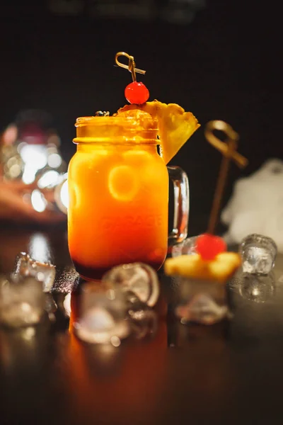 Cocktail orange på en svart bakgrund. Dekorerad med körsbär och omgiven av is och rök. — Stockfoto