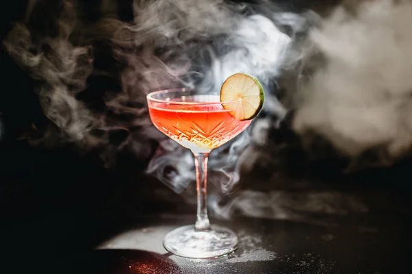 Alkoholhaltiga cocktail Greyhound, med vodka, likör, grapefruktjuice och is, svart bakgrund, alla i rök, garnerad med citron — Stockfoto