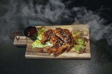 Teriyaki soslu susam ve pirinç siyah taş üzerine kızarmış tavuk budu. Yakın çekim. Siyah arka plan