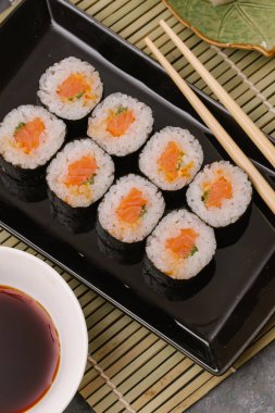 Japon restoranı, siyah tabakta suşi. Yemek çubuğu, zencefil, soya, üst görünüm, boşluk kopyalama