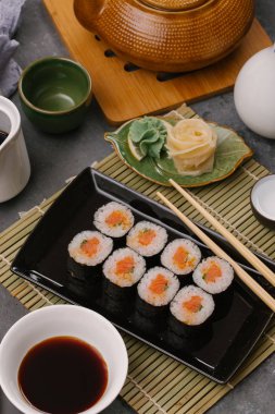 Japon restoranı, siyah tabakta suşi. Yemek çubuğu, zencefil, soya, üst görünüm, boşluk kopyalama