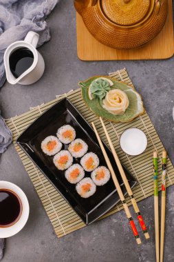 Japon restoranı, siyah tabakta suşi. Yemek çubuğu, zencefil, soya, üst görünüm, boşluk kopyalama
