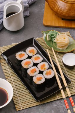 Japon restoranı, siyah tabakta suşi. Yemek çubuğu, zencefil, soya, üst görünüm, boşluk kopyalama