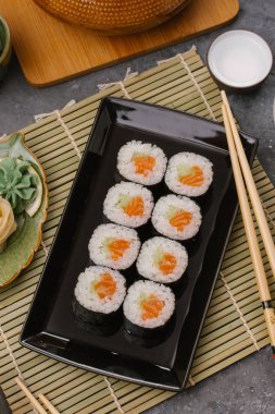 Bir Japon restoranında yemek. Seçici odak yakın kadar ton balığı bir ışık gri tabloda gri dikdörtgen plaka üzerinde siyah bir dikdörtgen plaka üzerinde rulo