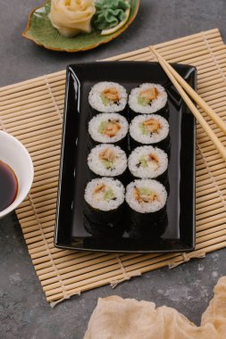 Bir Japon restoranında yemek. Seçici odak yakın kadar ton balığı bir ışık gri tabloda gri dikdörtgen plaka üzerinde siyah bir dikdörtgen plaka üzerinde rulo