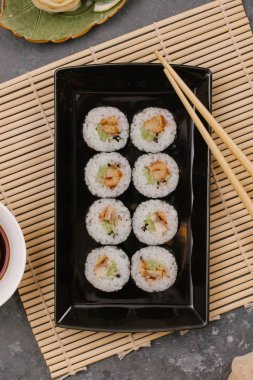 Bir Japon restoranında yemek. Seçici odak yakın kadar ton balığı bir ışık gri tabloda gri dikdörtgen plaka üzerinde siyah bir dikdörtgen plaka üzerinde rulo