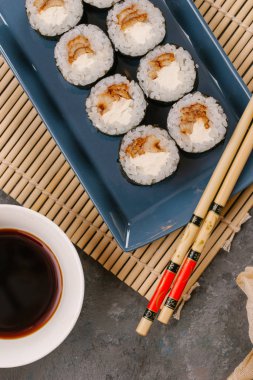 Bir Japon restoranında yemek. Seçici odak yakın kadar ton balığı bir ışık gri tabloda gri dikdörtgen plaka üzerinde siyah bir dikdörtgen plaka üzerinde rulo