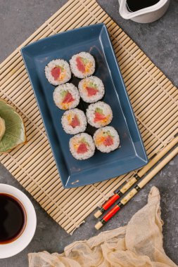 Bir Japon restoranında yemek. Seçici odak yakın kadar ton balığı bir ışık gri tabloda gri dikdörtgen plaka üzerinde siyah bir dikdörtgen plaka üzerinde rulo