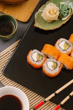Nori Maki Philadelphia suşi rulo Çiğ somon kümesiyle ve metin için yer siyah taş tablo zemin üzerine krem peynir. Uramaki ya da Futomaki suşi ile yakın kırmızı balık, soya sosu ve limon Üstten Görünüm