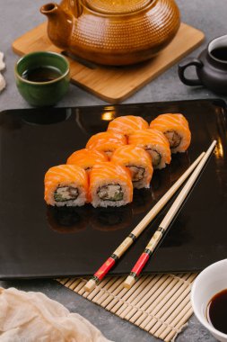 Nori Maki Philadelphia suşi rulo Çiğ somon kümesiyle ve metin için yer siyah taş tablo zemin üzerine krem peynir. Uramaki ya da Futomaki suşi ile yakın kırmızı balık, soya sosu ve limon Üstten Görünüm