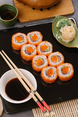 Nori Maki Philadelphia suşi rulo Çiğ somon kümesiyle ve metin için yer siyah taş tablo zemin üzerine krem peynir. Uramaki ya da Futomaki suşi ile yakın kırmızı balık, soya sosu ve limon Üstten Görünüm