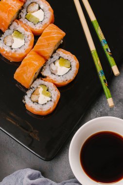 Nori Maki Philadelphia suşi rulo Çiğ somon kümesiyle ve metin için yer siyah taş tablo zemin üzerine krem peynir. Uramaki ya da Futomaki suşi ile yakın kırmızı balık, soya sosu ve limon Üstten Görünüm