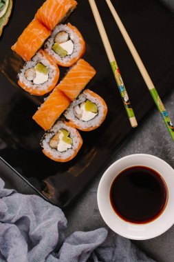 Nori Maki Philadelphia suşi rulo Çiğ somon kümesiyle ve metin için yer siyah taş tablo zemin üzerine krem peynir. Uramaki ya da Futomaki suşi ile yakın kırmızı balık, soya sosu ve limon Üstten Görünüm