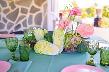 Tabaklar ve gözlüklerle yeşil masa örtüsü üzerinde renkli sebzeler ve çiçek aranjmanı, Zarif bir Yemek Atmosferi oluşturur