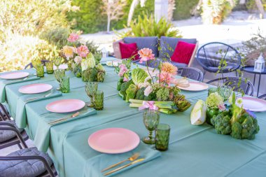 Çiçek süslemeli ve yeşil aksanlı güzel bir açık hava yemek masası, Toplama ve kutlamalar için mükemmel.