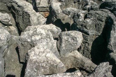 Deniz kenarında aşınmış büyük kayalar gün ortasında güneş tarafından yaktı.