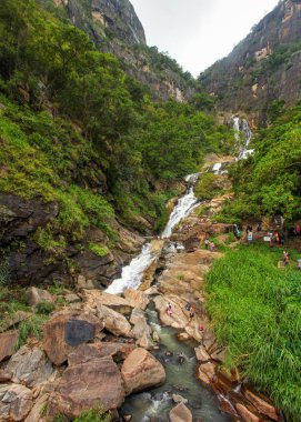 Ella, Sri Lanka - 13 Nisan 2017: turist Ravana Falls akışı yeşil yaylaları ormandaki bulutlu günde banyo.