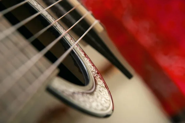 古典吉他六弦的细节 浅深度的焦点 与模糊的红色背景 — 图库照片