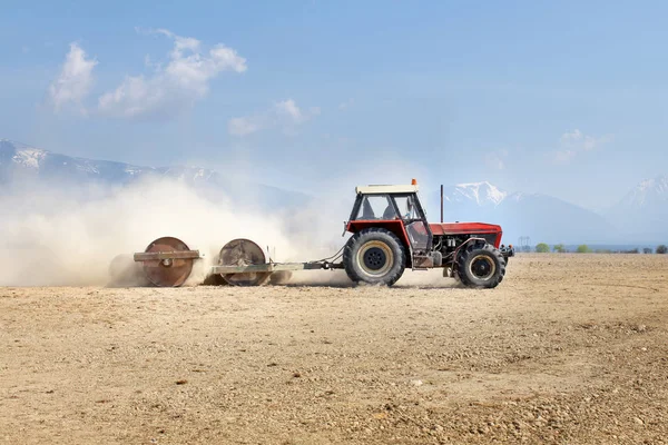 Traktor Húzza Nehéz Fém Görgők Készül Mező Tavasszal Hegyek Háttérben — Stock Fotó