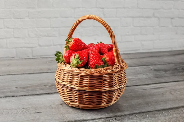 Basket with strawberries on gray wood desk.