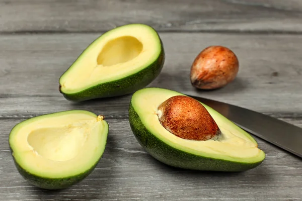 Aguacate Cortado Por Mitad Dos Semillas Cuchillo Cocinero Escritorio Madera —  Fotos de Stock