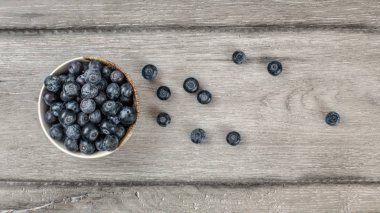 Tablo üstten görünüm - yaban mersini, bazıları rustik masanın üstüne dökülen küçük kase.