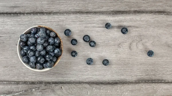 Tablo üstten görünüm - yaban mersini, bazıları rustik masanın üstüne dökülen küçük kase.