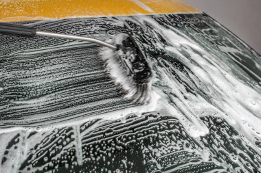 Sarı araba carwash, fırça darbeleri beyaz şampuanı ve köpük bırakarak yıkanmış ön cam.
