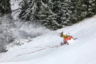 Yapım silahı püskürtme taze kar kar kayak pist üzerinde arka planda ağaçlar