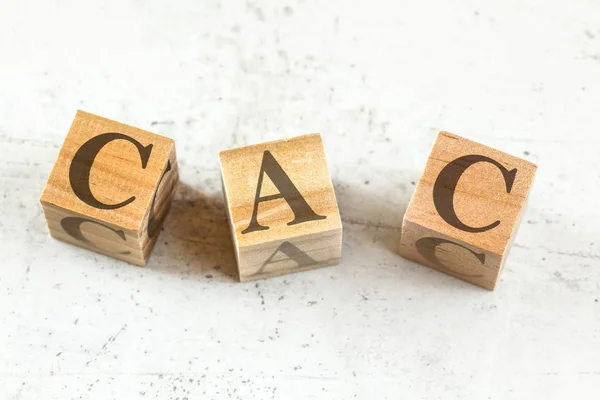 Три деревянных кубика с буквами CAC расшифровывается как Затраты на приобретение клиентов на белой доске . — стоковое фото