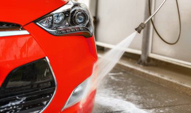 Kendini yıkanan kırmızı arabanın ön ışığı, cam üzerine püskürtme, yüksek basınçlı jet su akışı